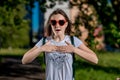 Beautiful schoolgirl girl. Summer nature after school. Glasses, heart is shaped. Smiles happily. Gestures of hands are Royalty Free Stock Photo