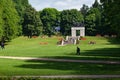 Beautiful sculpture in the Vigeland park on a sunny day with people resting in the green field, Oslo