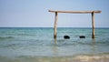 Beautiful sea landscape. High wooden swing decorated with colorful ribbons in a calm azure sea near the coastline.