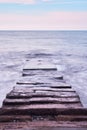 Beautiful sea landscape. Long stone sea pier breakwater goes deep into distance and waves break on it. Frozen photo using long Royalty Free Stock Photo