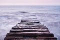 Beautiful sea landscape. Long stone sea pier breakwater goes deep into distance and waves break on it. Frozen photo using long Royalty Free Stock Photo