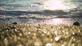 Pebble stones on the shore close up in the blurry sunset light in the distance background. Beautiful sea and pebbles background in