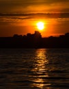 Beautiful sea sunrise. Dark silhouette of the city on the sea shore. Reflection on water surface. Royalty Free Stock Photo