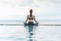Vacation of Beautiful Attractive Asian woman relaxing in yoga lotus pose on the pool above the beach Royalty Free Stock Photo
