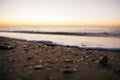 Beautiful sea waves foam closeup and sandy beach with seashells in sunrise light on tropical island. Waves in ocean at sunset. Royalty Free Stock Photo