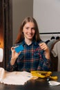 A beautiful seamstress sits at a desk, a young dressmaker talks about payment without cash. Hold a credit card in your hands Royalty Free Stock Photo