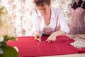 A beautiful seamstress woman in her own atelier makes a pattern