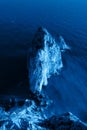 Seascape from above of a rock in the trendy classic blue color of the year.