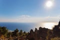 Beautiful seascape with ancient old ruined building and trees in the foreground. Bright sun and clouds over sea Royalty Free Stock Photo