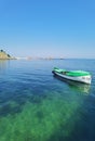 Beautiful seascape with a boat and green blue water, old lighthouse on the horizon, clear blue sky background