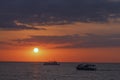 Beautiful seascape with boat in the sea at sunset with a colorful evening sky and a round disk of sun over the sea. Royalty Free Stock Photo