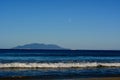 Seashores of New Zealand; beautiful seascape, bright blue ocean, a ship far away and moon over the sea.