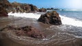 Beautiful seascape of ocean waves and shrap rocks on beach with black volcanic sand