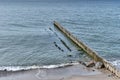 Beautiful seascape with old and new wooden breakwaters, stones, wave, sandy beach as background.