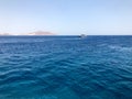 A beautiful seascape overlooking the blue salt sea, yellow sandy distant stone mountains on the tropical seaside resort and ships, Royalty Free Stock Photo