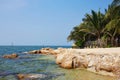 Beautiful seascape. Rocky beach, palm trees on the shore. In the background, a fisherman is fishing Royalty Free Stock Photo