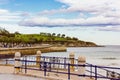 Beautiful seascape with rolling waves on a seashore behind blue metal fence on a promenade in summer day. Green hills on Royalty Free Stock Photo