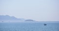 A beautiful seascape, a sailboat floating in the distance amidst majestic mountains.