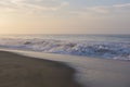 Beautiful seascape shot of the Indian ocean at sunrise with orange sand, a low tide with big white foamy waves and a blue orange Royalty Free Stock Photo