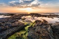 Beautiful seascape. Sunset over the sea rock and shore. A thin orange line at the horizon and the blue sky background and moss on