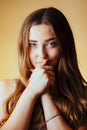 Beautiful seductive girl with hands near face on orange colored background, young woman portrait, concept of female beauty Royalty Free Stock Photo