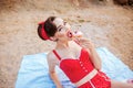 Beautiful seductive pin up girl in swimsuit eating cream cake