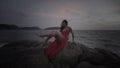 Beautiful seductive woman in red dress enjoying herself on rocks by the sea Royalty Free Stock Photo