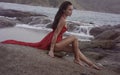 Beautiful seductive woman in red dress enjoying herself on rocks by the sea Royalty Free Stock Photo