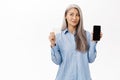 Beautiful senior asian woman thinking, showing smartphone and credit card, smiling thoughtful, concept of online Royalty Free Stock Photo