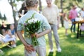 Beautiful senior birthday woman receiving flowers from grandchildren. Concept of garden birthday party for elderly woman Royalty Free Stock Photo