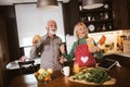 Senior couple is dancing and smiling while cooking together in kitchen Royalty Free Stock Photo