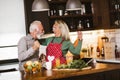 Senior couple is dancing and smiling while cooking together in kitchen Royalty Free Stock Photo