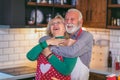 Beautiful senior couple is dancing and smiling while cooking together in kitchen Royalty Free Stock Photo