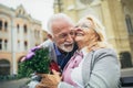 Senior couple dating outdoors. Man giving his wife present and flowers Royalty Free Stock Photo