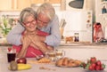 Beautiful senior couple having breakfast at home, starting morning with a warm hug. Hot cappuccino croissant on the table Royalty Free Stock Photo