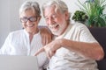 Beautiful senior couple  using laptop computer laughing. Serene elderly people enjoying technology and social Royalty Free Stock Photo