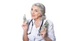 Beautiful senior female doctor posing against white background with banknotes