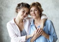 Beautiful senior mom and her adult daughter are hugging, looking at camera and smiling. At Home Royalty Free Stock Photo