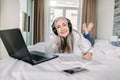 Beautiful senior smiling woman lying down the bed with legs raised slightly, using laptop and making notes in her Royalty Free Stock Photo