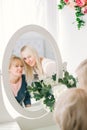 Beautiful senior woman and blonde daughter looking at reflection in mirror in white studio Royalty Free Stock Photo