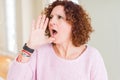 Beautiful senior woman wearing pink sweater shouting and screaming loud to side with hand on mouth Royalty Free Stock Photo