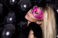 Beautiful sensual blonde woman with carnival mask , standing on a background of black balloons Royalty Free Stock Photo