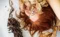 Beautiful sensual portrait of a young sexy woman redhead artfully lying between leaves of dry, withered decorative banana tree on Royalty Free Stock Photo