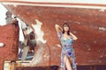 Beautiful, sensual and fashion model posing in front of old rusty boat.