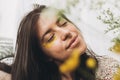 Beautiful sensual woman with yellow petals on face posing with wildflowers in sunny room. Portrait of young brunette in boho dress Royalty Free Stock Photo