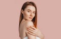 Beautiful sensual young girl with clean skin on a pink background with a mockup. Topless woman in a towel. The concept of spa Royalty Free Stock Photo