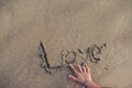 Beautiful sentence was written LOVE on the sand by beautiful young woman finger at the adorable beach Royalty Free Stock Photo