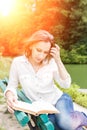 Beautiful serious girl reads book in sunset beams