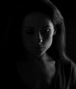 Beautiful serious mysterious woman in darkness looking dramatic. Closeup portrait in dark shadow low key. Art. closeup front face
