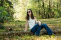 A beautiful serious teen brunette girl wearing sunglasses looking away from the camera towards the future in a wooded Royalty Free Stock Photo